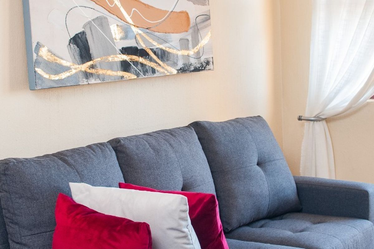 A cozy living room area featuring neutral wall tones, tiled flooring, and a window fitted with a curtain rod.