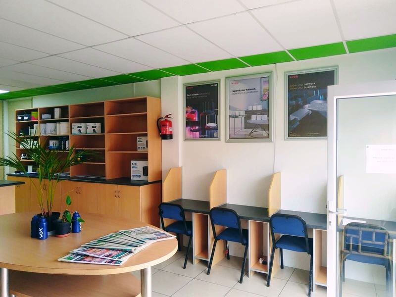 A functional office space featuring built-in shelving units, individual workstations, and a suspended ceiling, suitable for a professional retail or business environment.