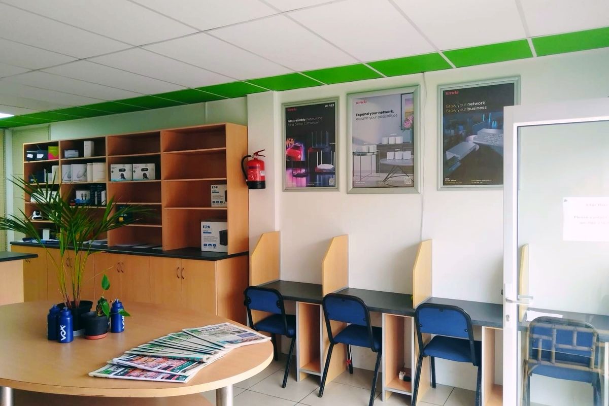 A functional office space featuring built-in shelving units, individual workstations, and a suspended ceiling, suitable for a professional retail or business environment.
