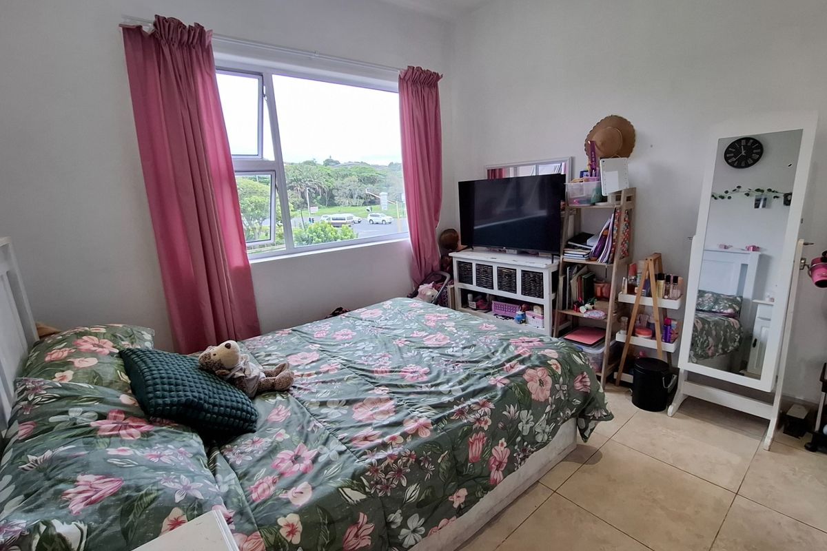 A bedroom featuring tiled flooring and a large window providing natural light and an exterior view.