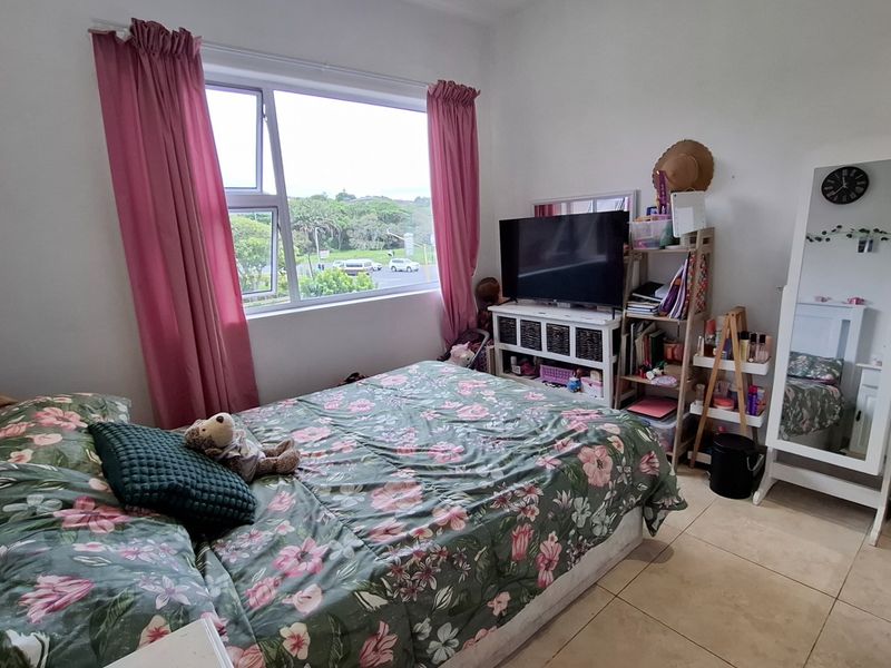 A bedroom featuring tiled flooring and a large window providing natural light and an exterior view.