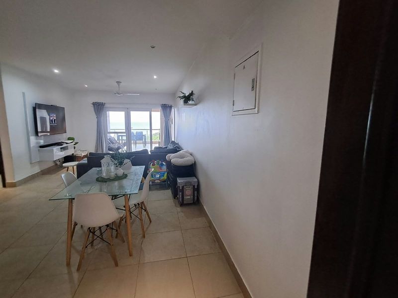 Open-plan living and dining area featuring tiled flooring, recessed lighting, and direct access to a balcony through sliding glass doors.