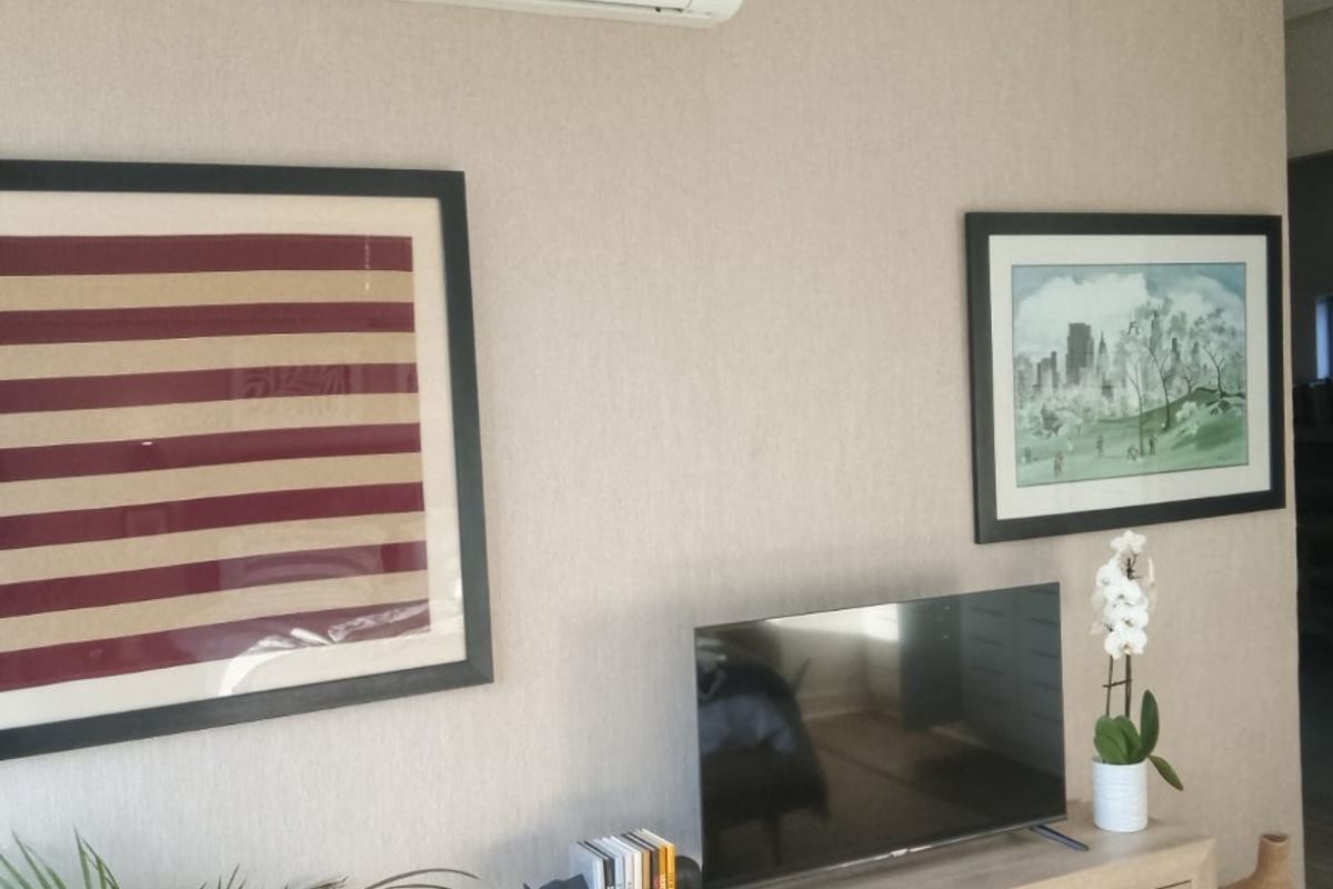 A living room wall featuring textured wallpaper and a wall-mounted air conditioning unit.