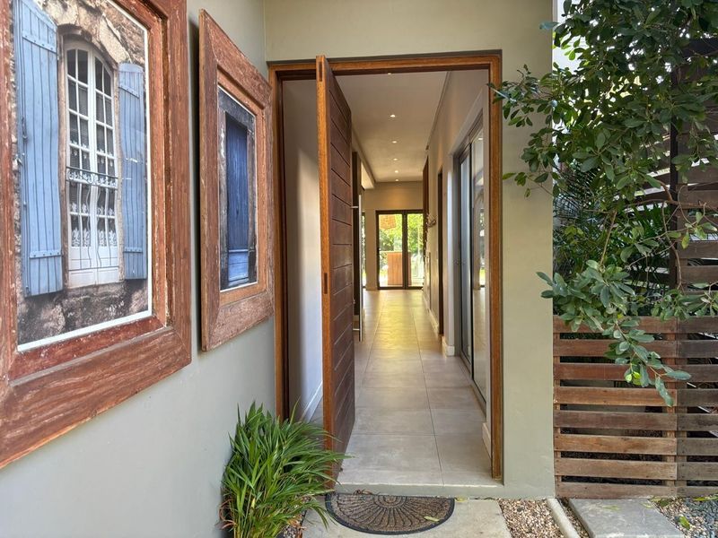 Inviting entrance featuring a modern timber pivot door, tiled flooring, and recessed lighting, leading into a bright, open-plan interior space.