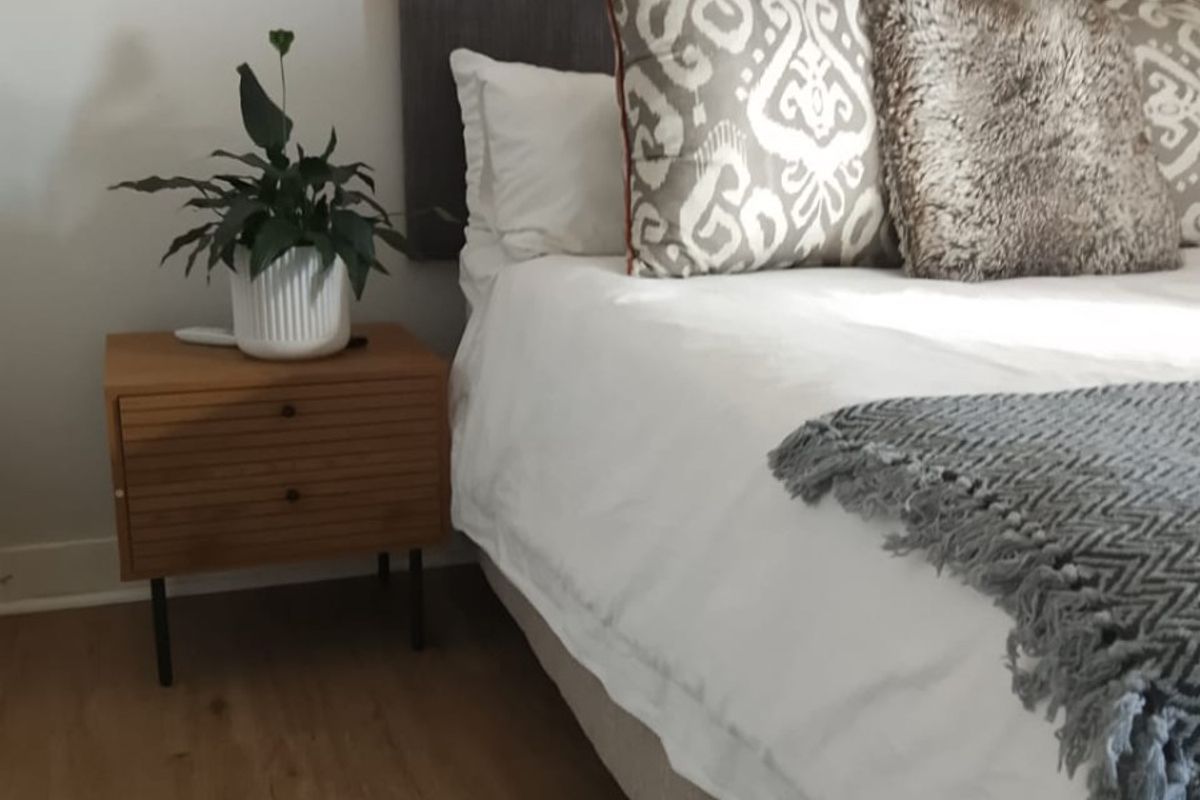 A well-maintained bedroom featuring modern laminate flooring and a wall-mounted light fixture, creating a comfortable and inviting sleeping space.