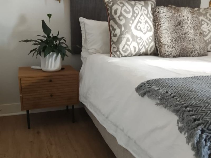 A well-maintained bedroom featuring modern laminate flooring and a wall-mounted light fixture, creating a comfortable and inviting sleeping space.