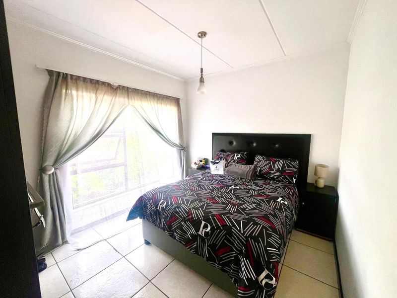 A bedroom featuring tiled flooring, a large window with natural light, and a ceiling pendant light fixture.