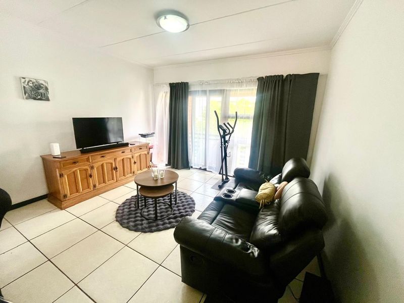 A living room featuring tiled flooring and a sliding glass door providing access to the exterior.