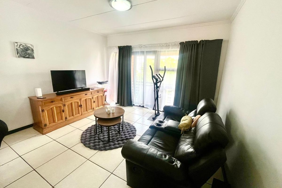 A living room featuring tiled flooring and a sliding glass door providing access to the exterior.