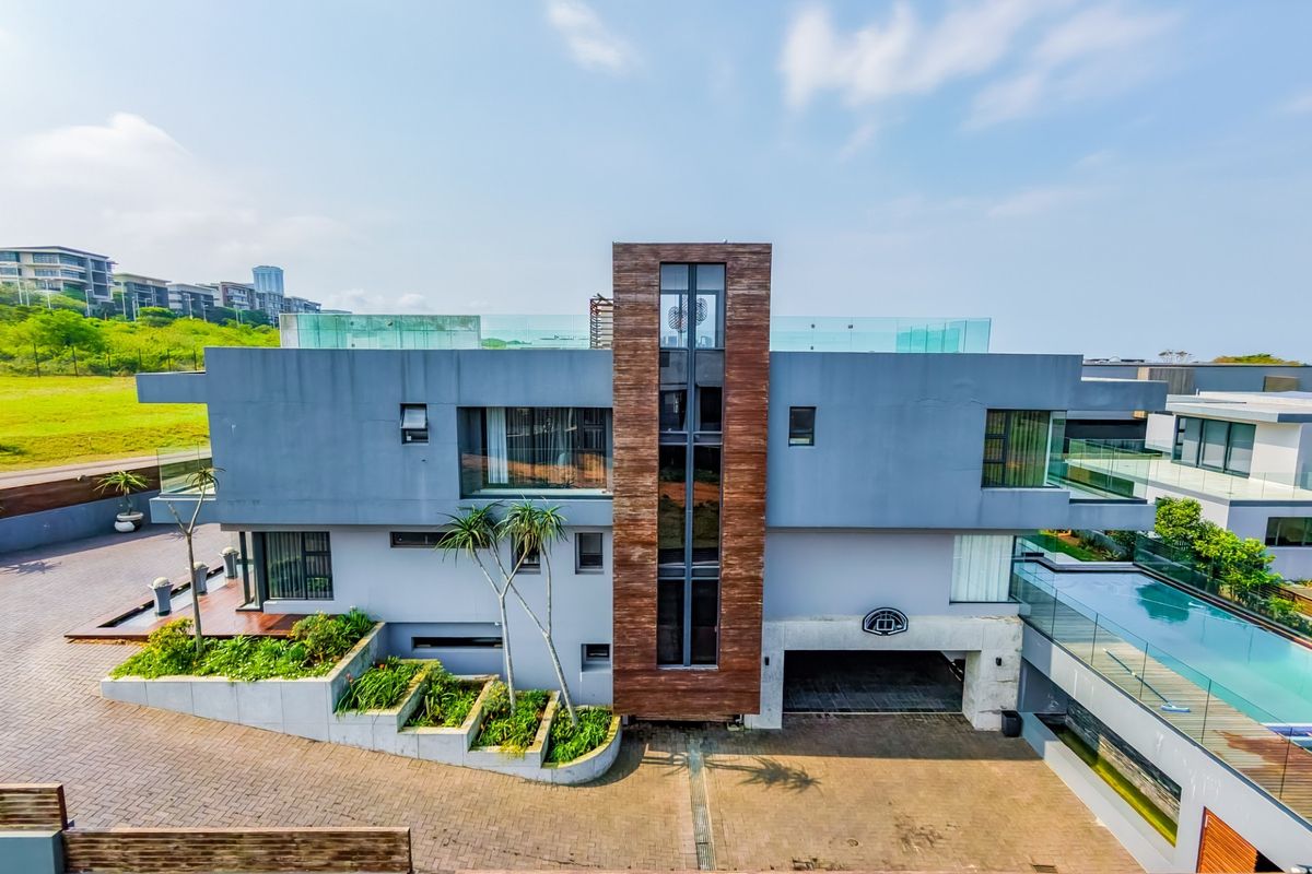 Modern multi-level residence featuring a swimming pool, expansive roof terrace, timber accents, and a paved driveway with integrated landscaping.
