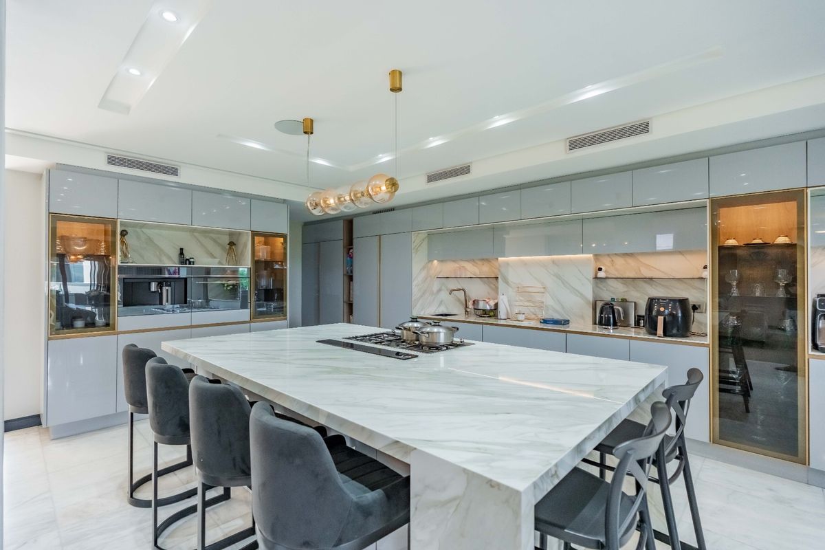 Modern luxury kitchen featuring a large marble island with integrated gas cooktop, sleek high-gloss cabinetry, and premium built-in appliances.