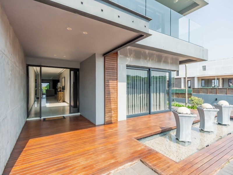 Modern covered patio featuring high-quality timber decking, a built-in water feature, and seamless access to the interior through large sliding glass doors.