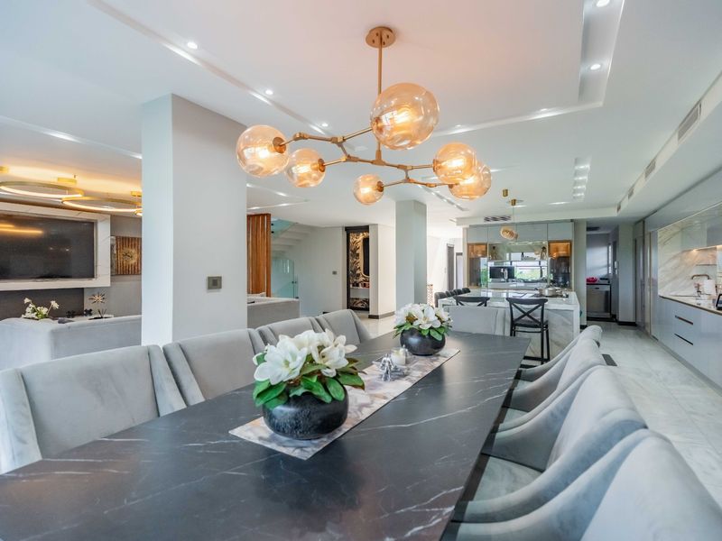 Spacious open-plan living, dining, and kitchen area featuring high-end finishes, marble flooring, modern cabinetry, and sophisticated recessed and pendant lighting throughout.
