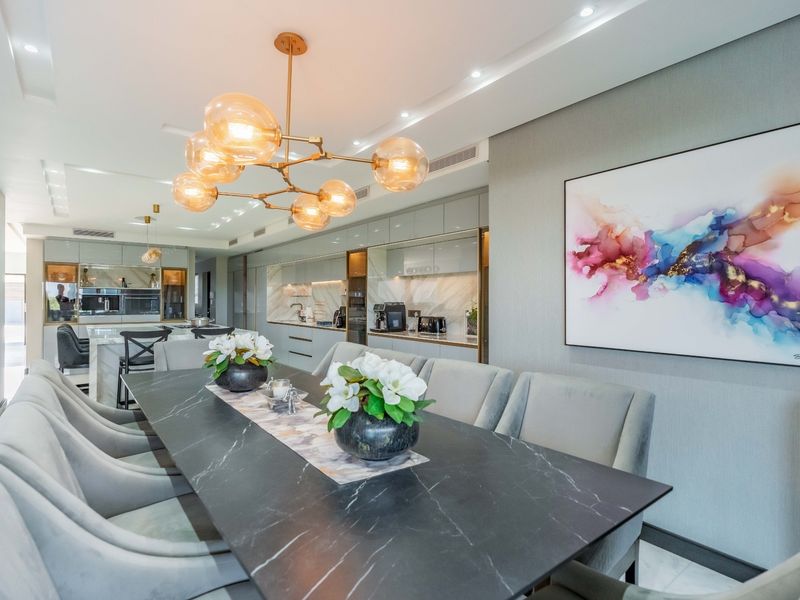 Modern open-plan dining and kitchen area featuring high-end finishes, sleek cabinetry, integrated appliances, and elegant pendant lighting in a sophisticated, contemporary setting.