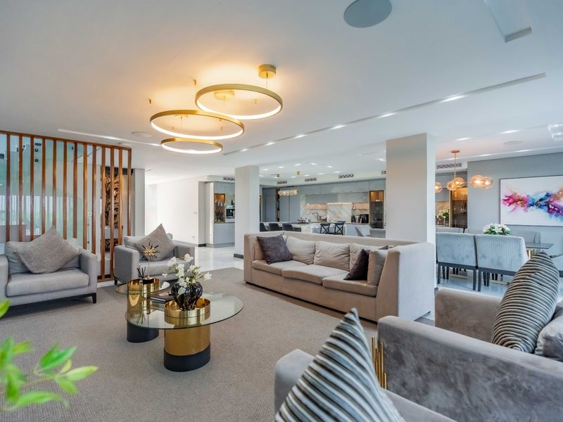 Spacious open-plan living, dining, and kitchen area featuring modern finishes, recessed lighting, a timber slat divider, and a high-end marble kitchen island.