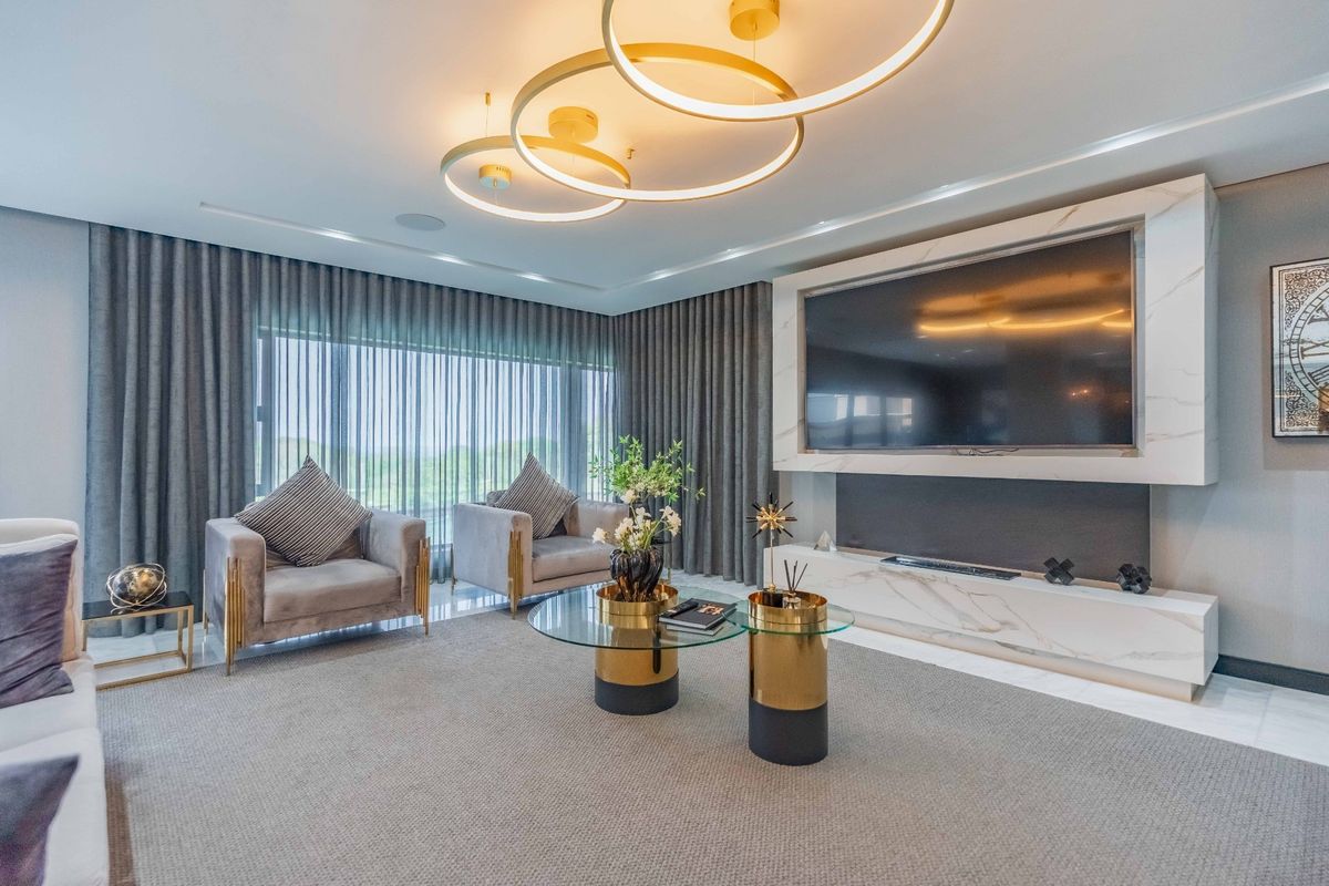 A modern, high-end living room featuring a sophisticated marble media wall, recessed ceiling lighting, and floor-to-ceiling drapery, creating a luxurious and polished atmosphere.