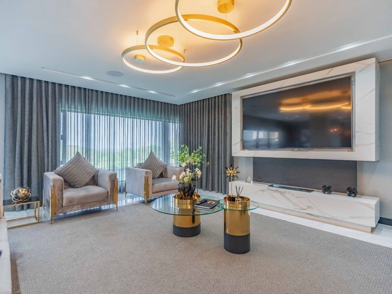 A modern, high-end living room featuring a sophisticated marble media wall, recessed ceiling lighting, and floor-to-ceiling drapery, creating a luxurious and polished atmosphere.