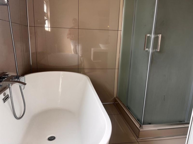 Modern bathroom featuring a sleek freestanding bathtub, a separate glass-enclosed shower, and contemporary wall and floor tiling.