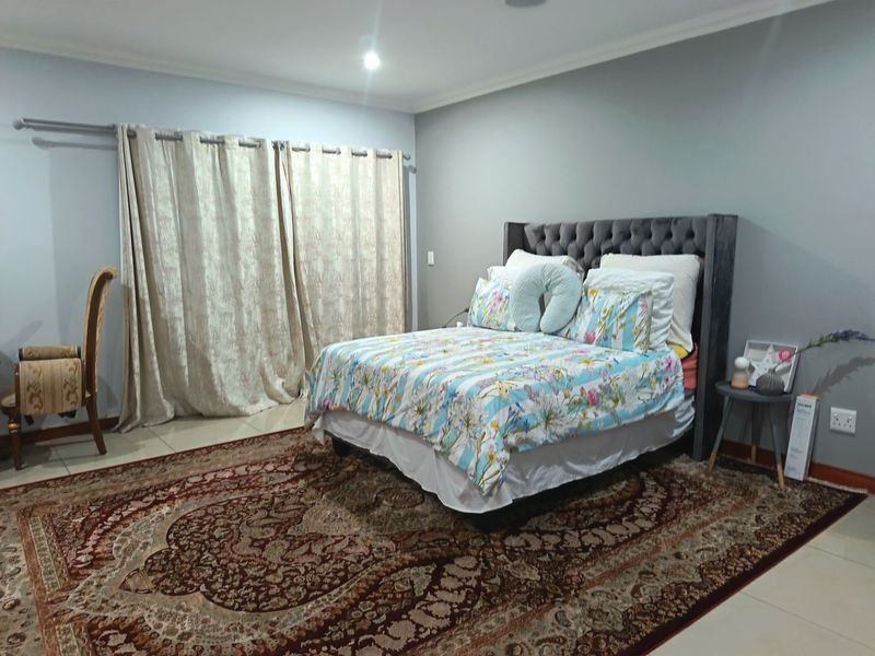 A spacious bedroom featuring neutral grey walls, tiled flooring, and recessed lighting, providing a clean and functional living space.