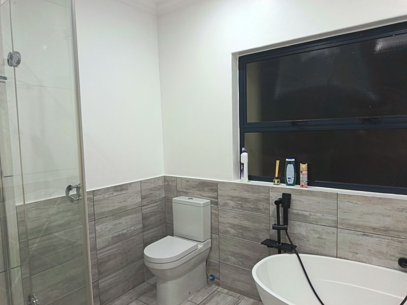 Modern bathroom featuring a glass shower enclosure, a freestanding bathtub, and contemporary wood-look tile finishes.