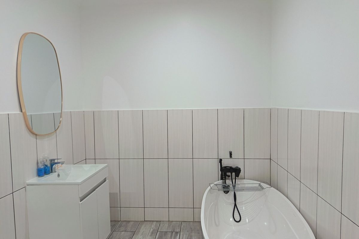Modern bathroom featuring a sleek freestanding bathtub, contemporary vanity cabinet with basin, and stylish vertical wall tiling.