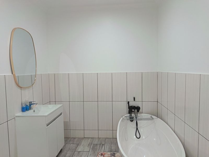 Modern bathroom featuring a sleek freestanding bathtub, contemporary vanity cabinet with basin, and stylish vertical wall tiling.