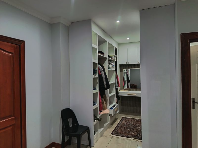 A well-organized walk-in closet area featuring extensive built-in cabinetry, a dedicated vanity station, and modern recessed lighting.