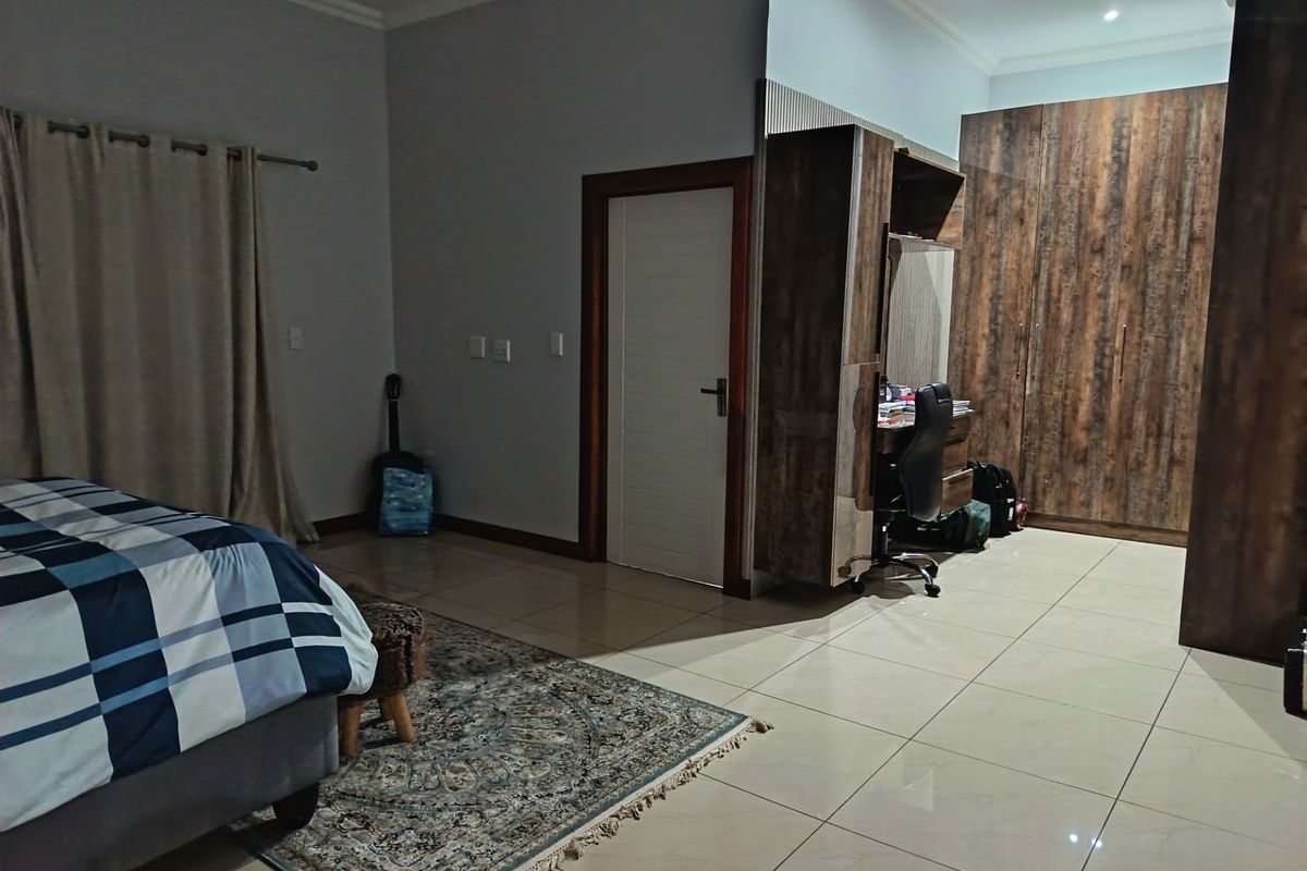 Spacious bedroom featuring large built-in wooden cupboards, a dedicated built-in desk area, and neutral tiled flooring throughout.