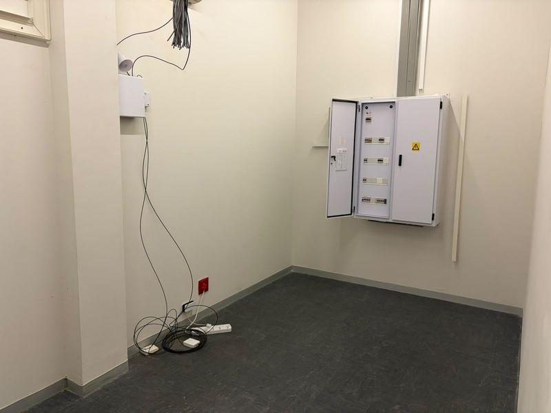 A functional utility space featuring an electrical distribution board and exposed data cabling, suitable for server or infrastructure storage.