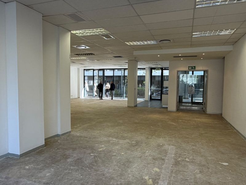 Open plan office space featuring a suspended ceiling, recessed lighting, and large glass windows providing natural light and exterior views.
