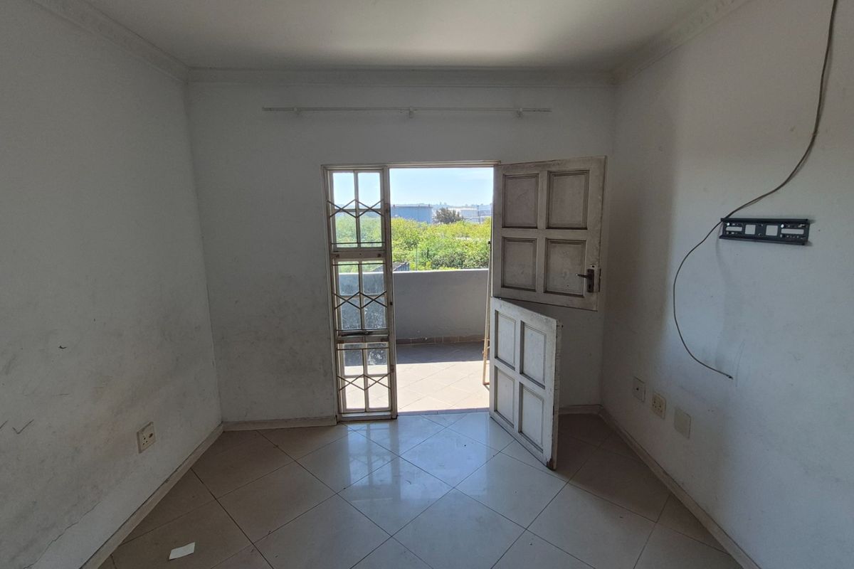 An empty bedroom featuring tiled flooring, coving, and direct access to a balcony through a security gate.
