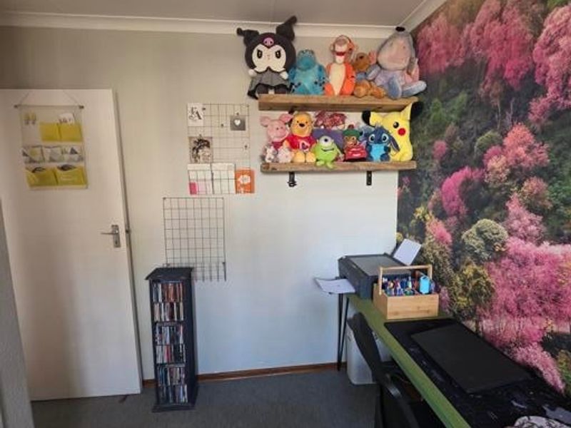 A bedroom featuring a built-in desk area, wall-mounted shelving, and a decorative feature wall, providing a functional space for work or study.