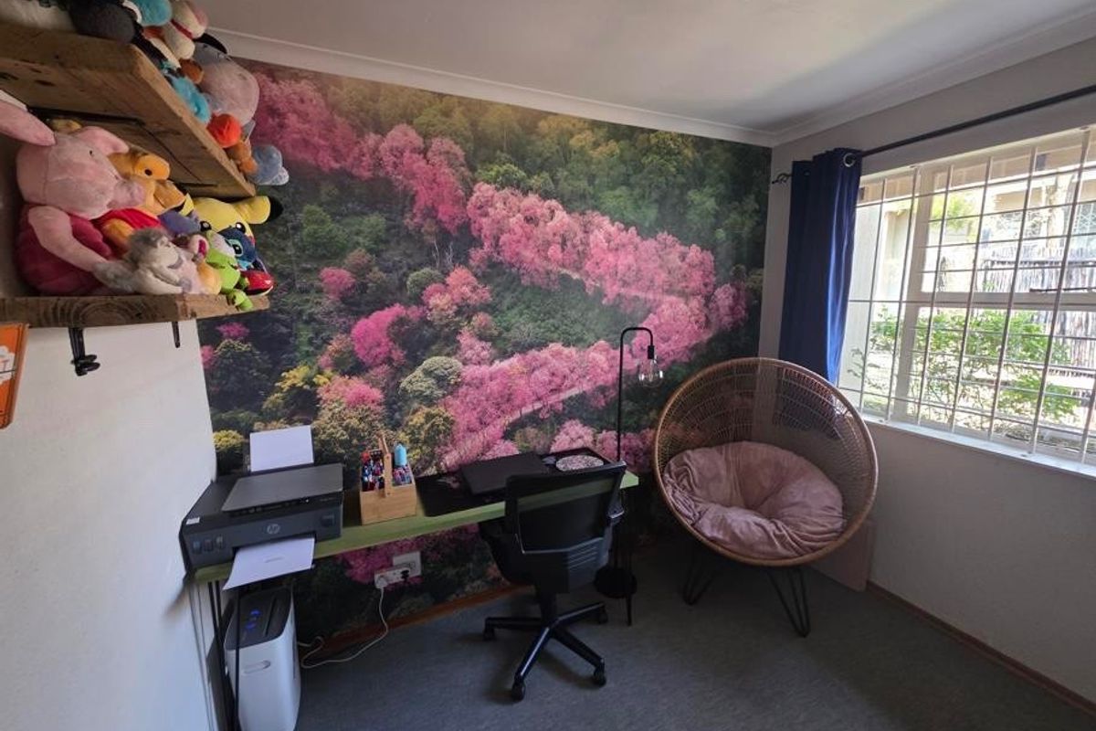 A bedroom featuring a decorative mural wall, built-in shelving, and a window fitted with security bars.