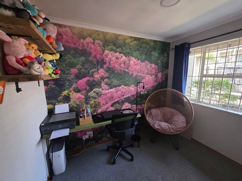 A bedroom featuring a decorative mural wall, built-in shelving, and a window fitted with security bars.
