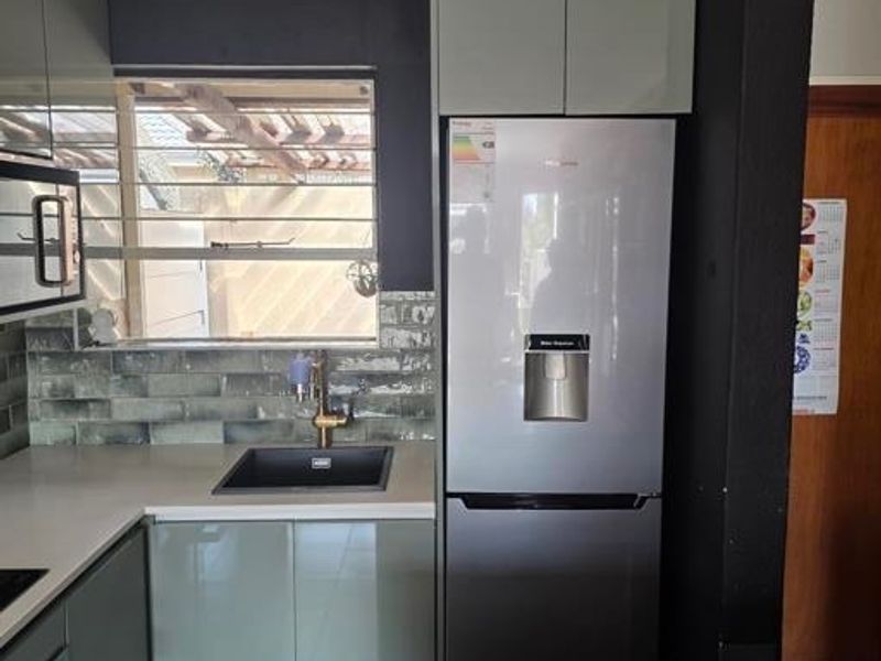 Modern kitchen featuring sleek cabinetry, stone countertops, a stylish tiled backsplash, and integrated appliances, offering a clean and functional culinary space.