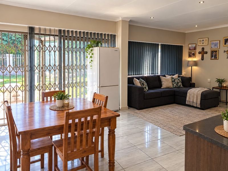 Spacious open-plan living and dining area featuring tiled flooring, recessed lighting, and large sliding doors with security gates leading to the garden.