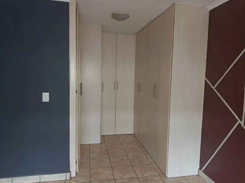 A bedroom area featuring built-in cupboards and tiled flooring, offering a clean and functional space ready for personalization.