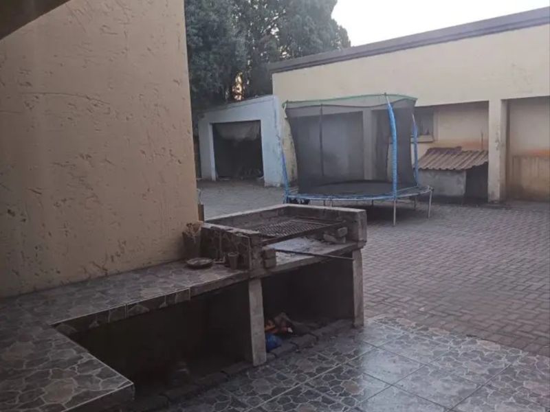 Outdoor patio area featuring a built-in braai, tiled flooring, and a paved courtyard space.