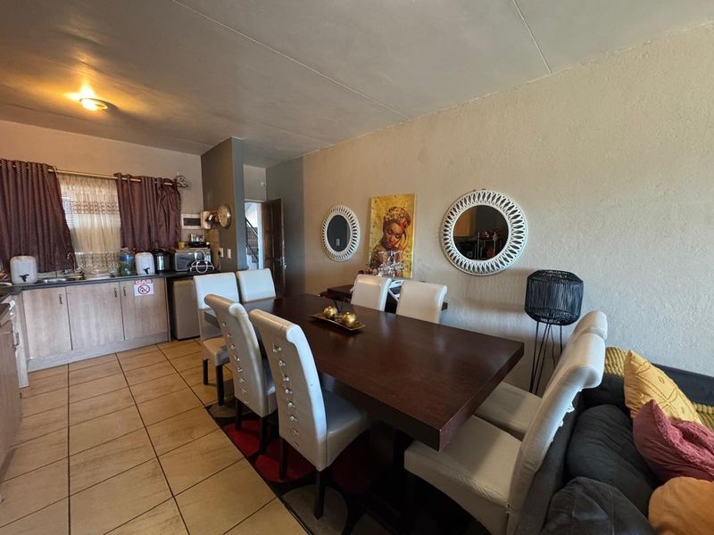 Open plan living and dining area featuring tiled flooring and an integrated kitchen space with cabinetry and sink.