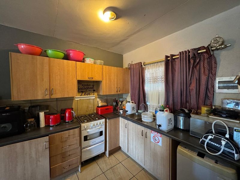 A functional kitchen featuring laminate cabinetry, a gas stove, and tiled flooring. The space would benefit from cosmetic updates to modernize the finishes.