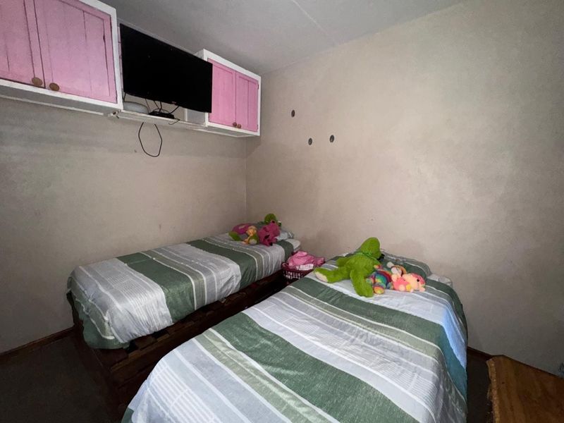 A bedroom featuring built-in overhead cabinetry and plain wall finishes, requiring cosmetic updates to improve the overall aesthetic and condition.