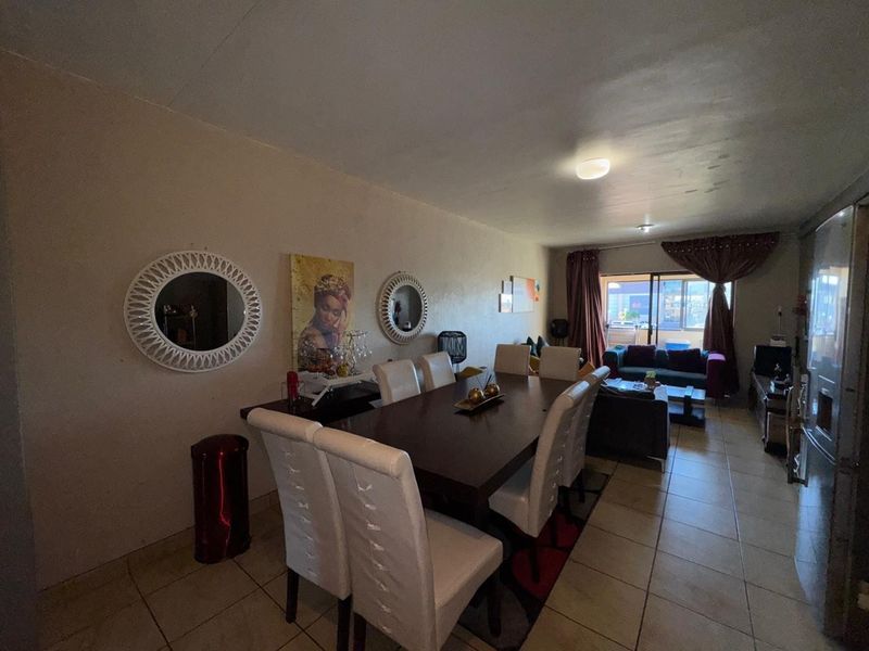 Open-plan living and dining area featuring tiled flooring and access to a balcony through sliding glass doors.