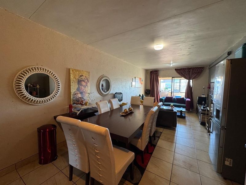 An open-plan living and dining area featuring tiled flooring and a sliding glass door leading to an outdoor space.