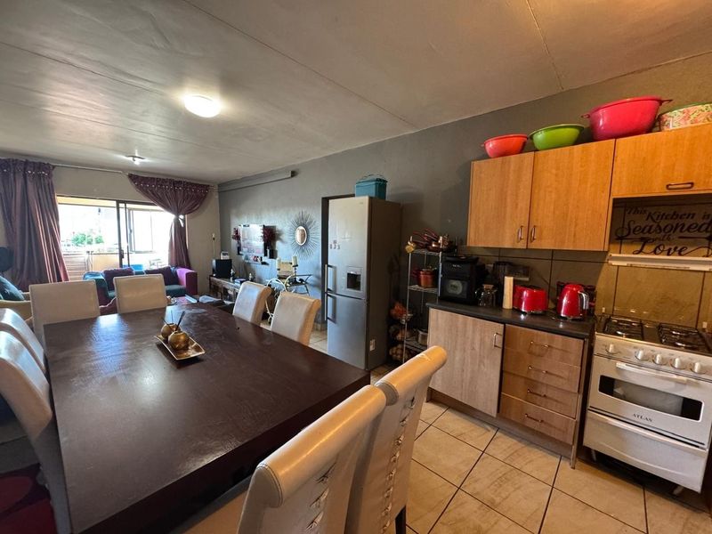 Open-plan living and dining area featuring a functional kitchen with built-in cabinetry, gas stove, and direct access to a balcony through sliding glass doors.