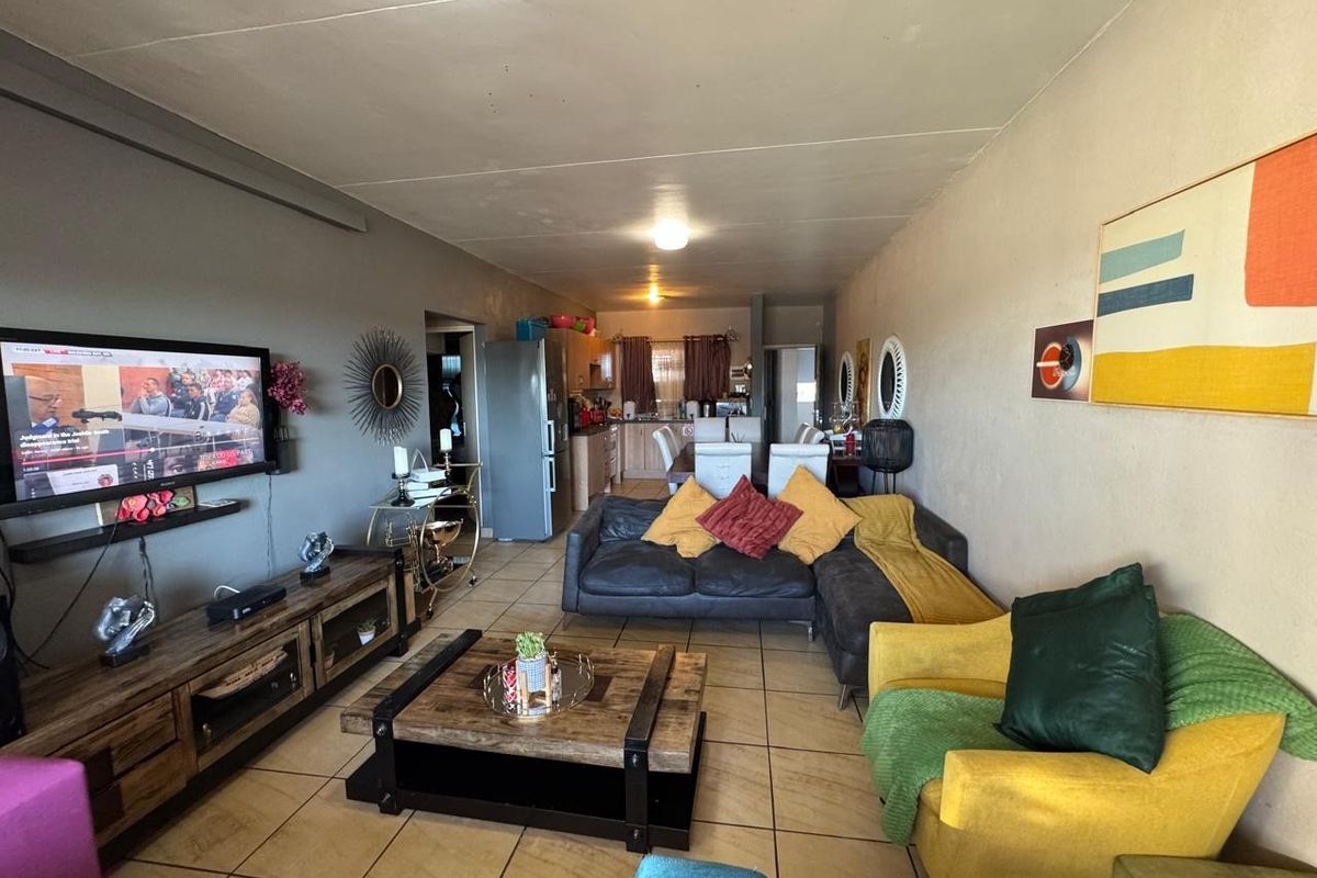 Open-plan living and dining area featuring tiled flooring and an integrated kitchen space, offering a functional layout for modern apartment living.