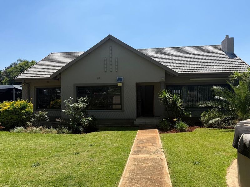 Front elevation of a single-story house featuring a tiled roof, concrete walkway, and established garden.