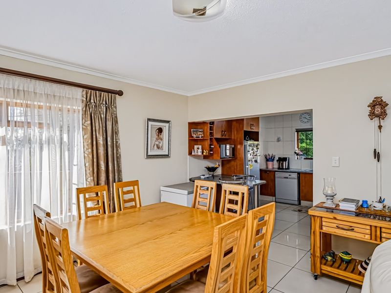 Open plan dining area flowing into a functional kitchen with tiled flooring and built-in cabinetry.