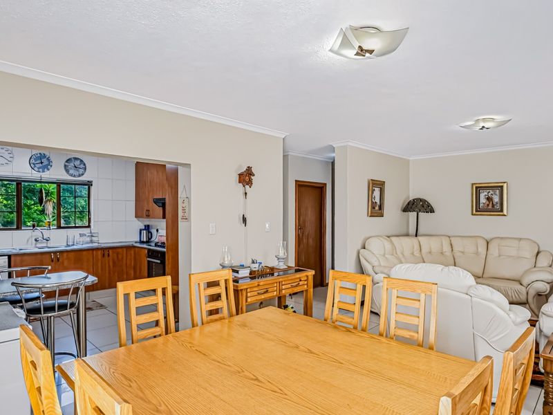 Spacious open-plan living and dining area featuring a functional kitchen with built-in cabinetry and tiled finishes, creating a comfortable and connected family space.