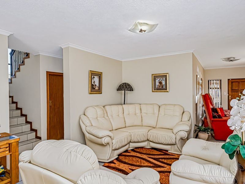 Spacious living area featuring neutral wall tones, tiled flooring, and an integrated staircase leading to the upper level.