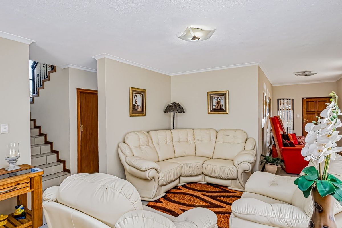 Spacious living area featuring neutral wall tones, tiled flooring, and an integrated staircase leading to the upper level.
